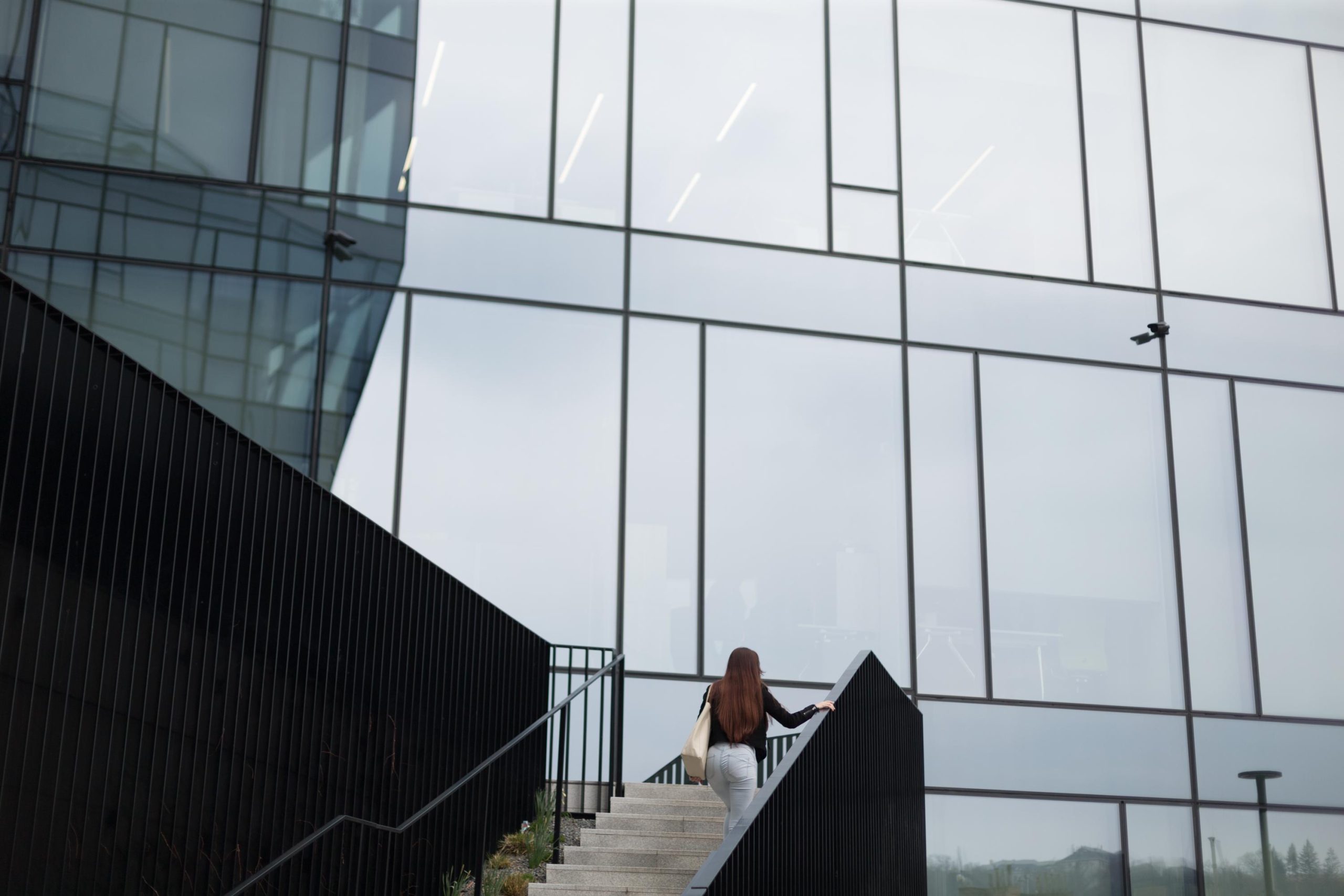 A woman is leisurely walking up the stairs of a tall building