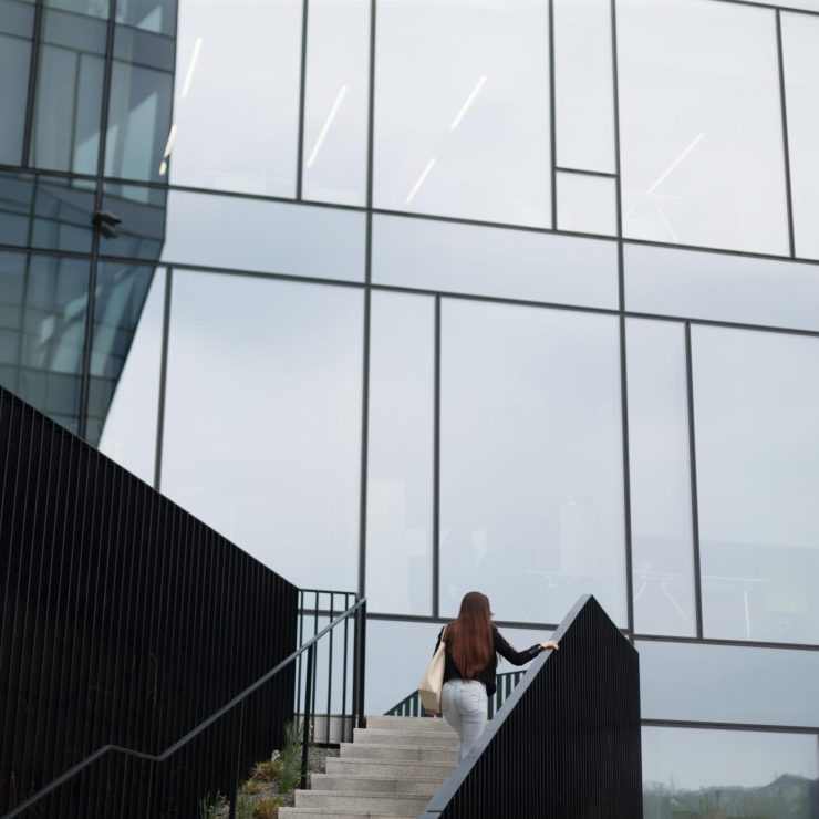 A woman is leisurely walking up the stairs of a tall building