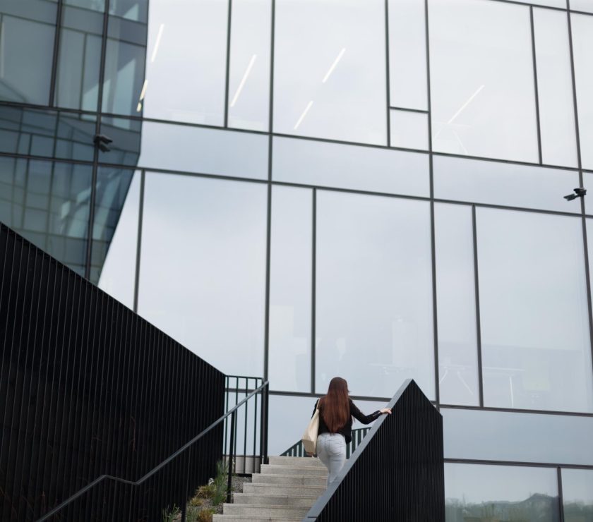 A woman is leisurely walking up the stairs of a tall building