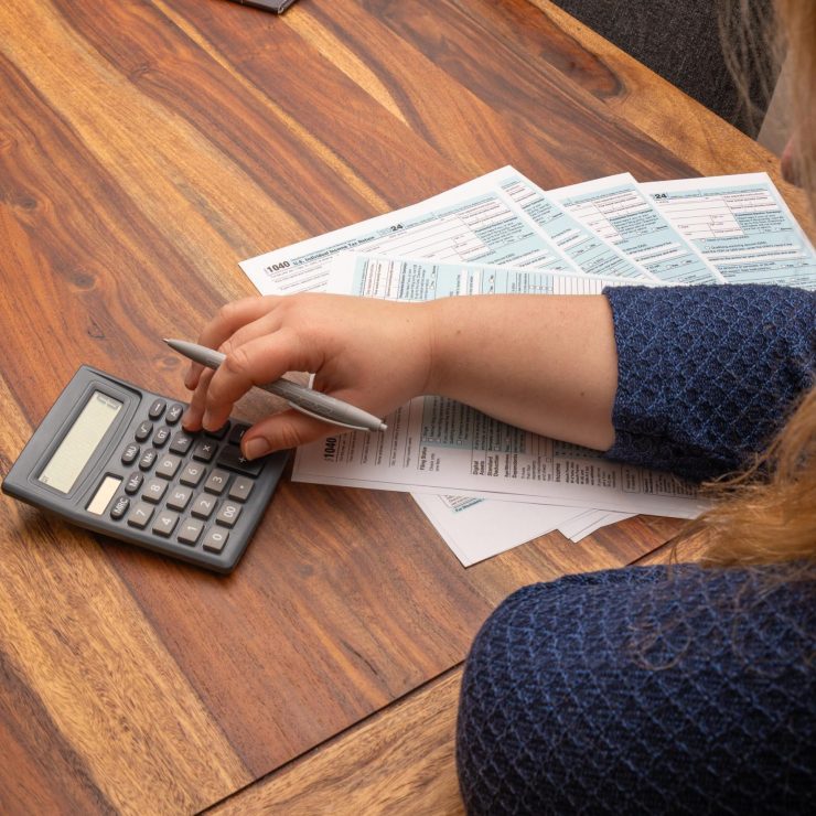 Woman managing finances by filling out 1040 US income tax form at a wooden desk