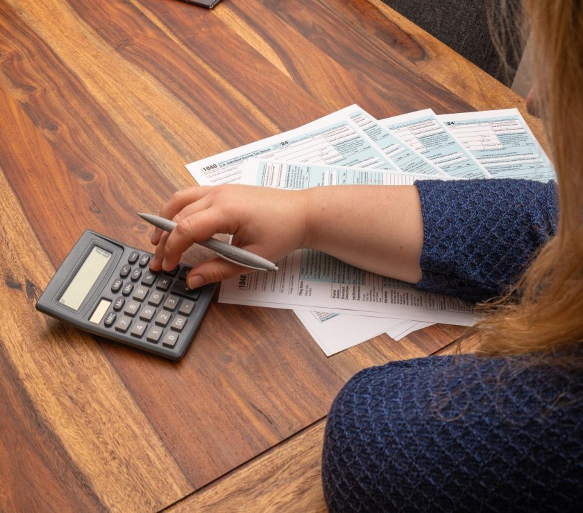 Woman managing finances by filling out 1040 US income tax form at a wooden desk