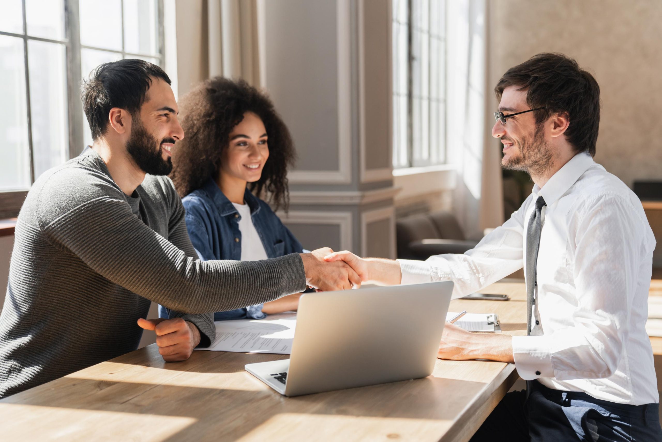 Couple handshake mortgage officer worker, accept bank loan terms and rates feel satisfied.