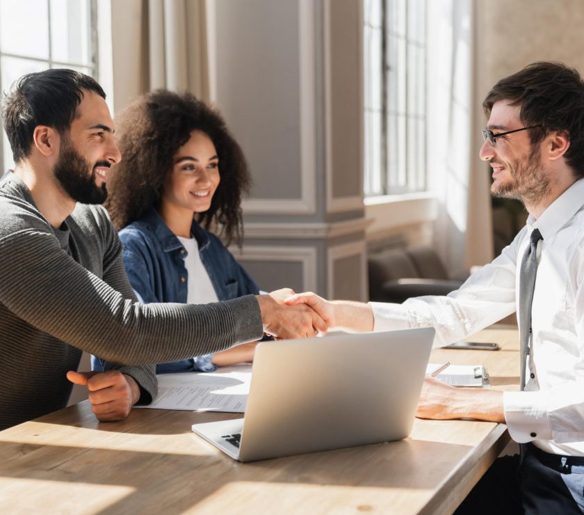 Couple handshake mortgage officer worker, accept bank loan terms and rates feel satisfied.