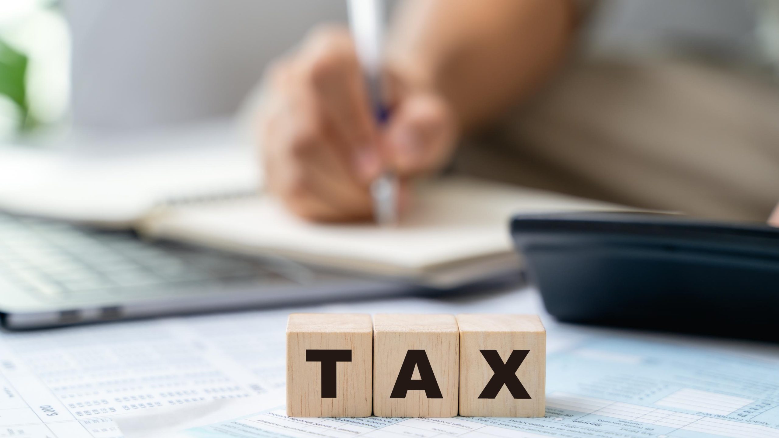 Man is calculating annual tax, monthly expenses with calculator and filling form of Individual Income Tax Return. Season to pay Tax and Budget planning concept.