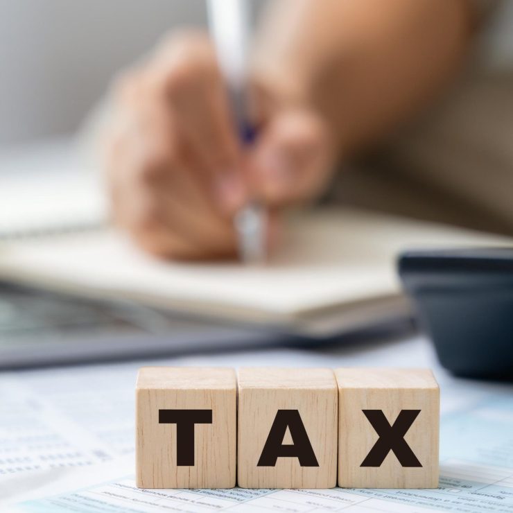 Man is calculating annual tax, monthly expenses with calculator and filling form of Individual Income Tax Return. Season to pay Tax and Budget planning concept.