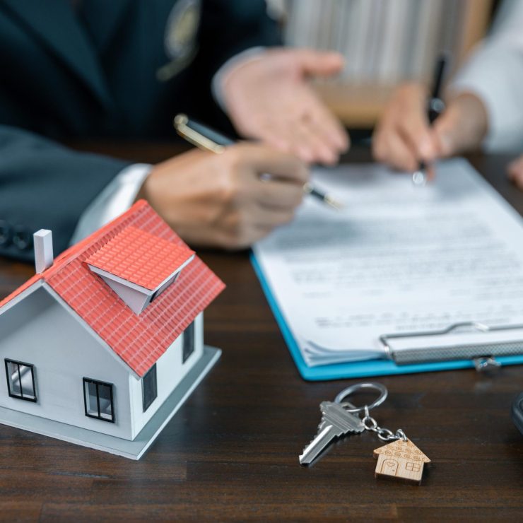 Discussion with a real estate agent, House model with agent and customer discussing for the contract to buy, get insurance or loan real estate or property. approved mortgage application form.