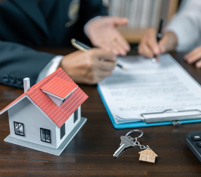 Discussion with a real estate agent, House model with agent and customer discussing for the contract to buy, get insurance or loan real estate or property. approved mortgage application form.