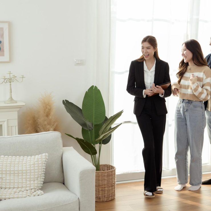 Real Estate Agent Showing a Modern Apartment to Young Couple During Daylight Hours in Bright Living Room