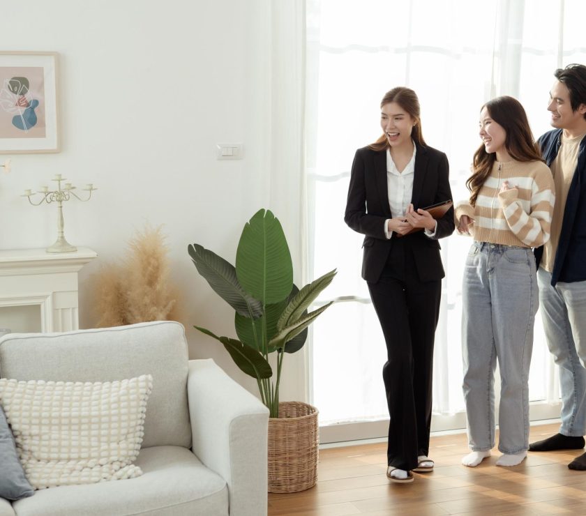 Real Estate Agent Showing a Modern Apartment to Young Couple During Daylight Hours in Bright Living Room
