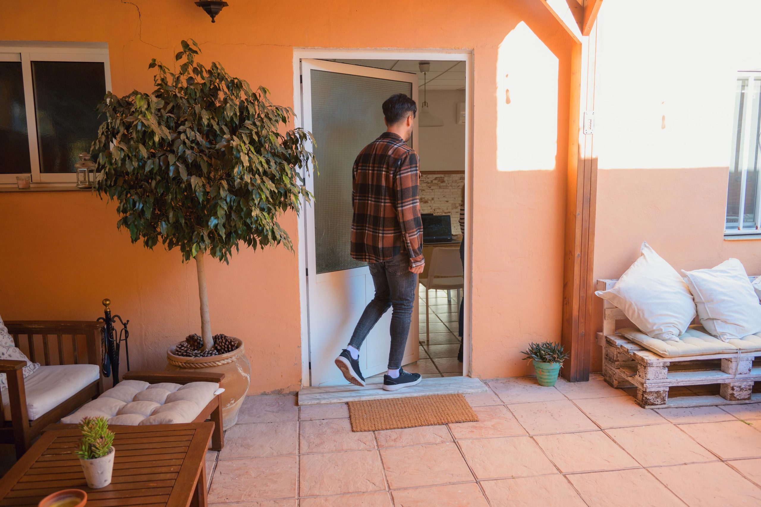 Man entering home on a cozy patio decked with wooden furniture