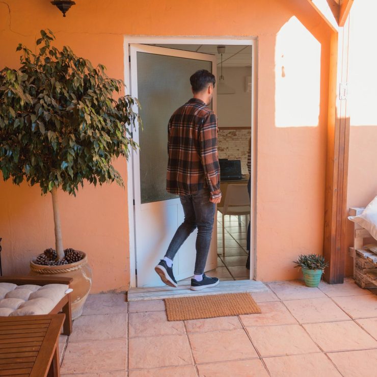 Man entering home on a cozy patio decked with wooden furniture