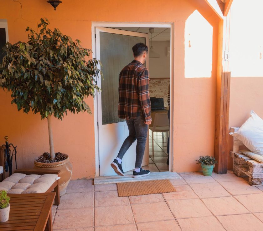 Man entering home on a cozy patio decked with wooden furniture