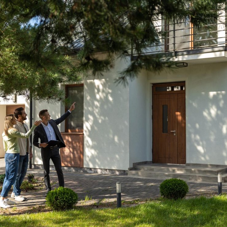 Agent showing house entrance to clients in suburban setting