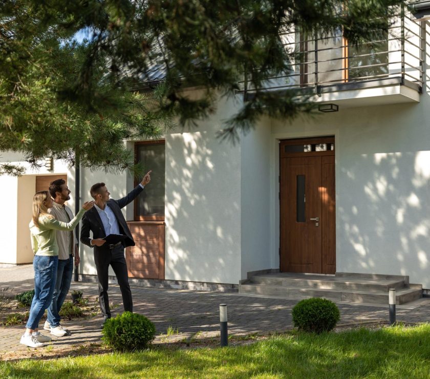 Agent showing house entrance to clients in suburban setting